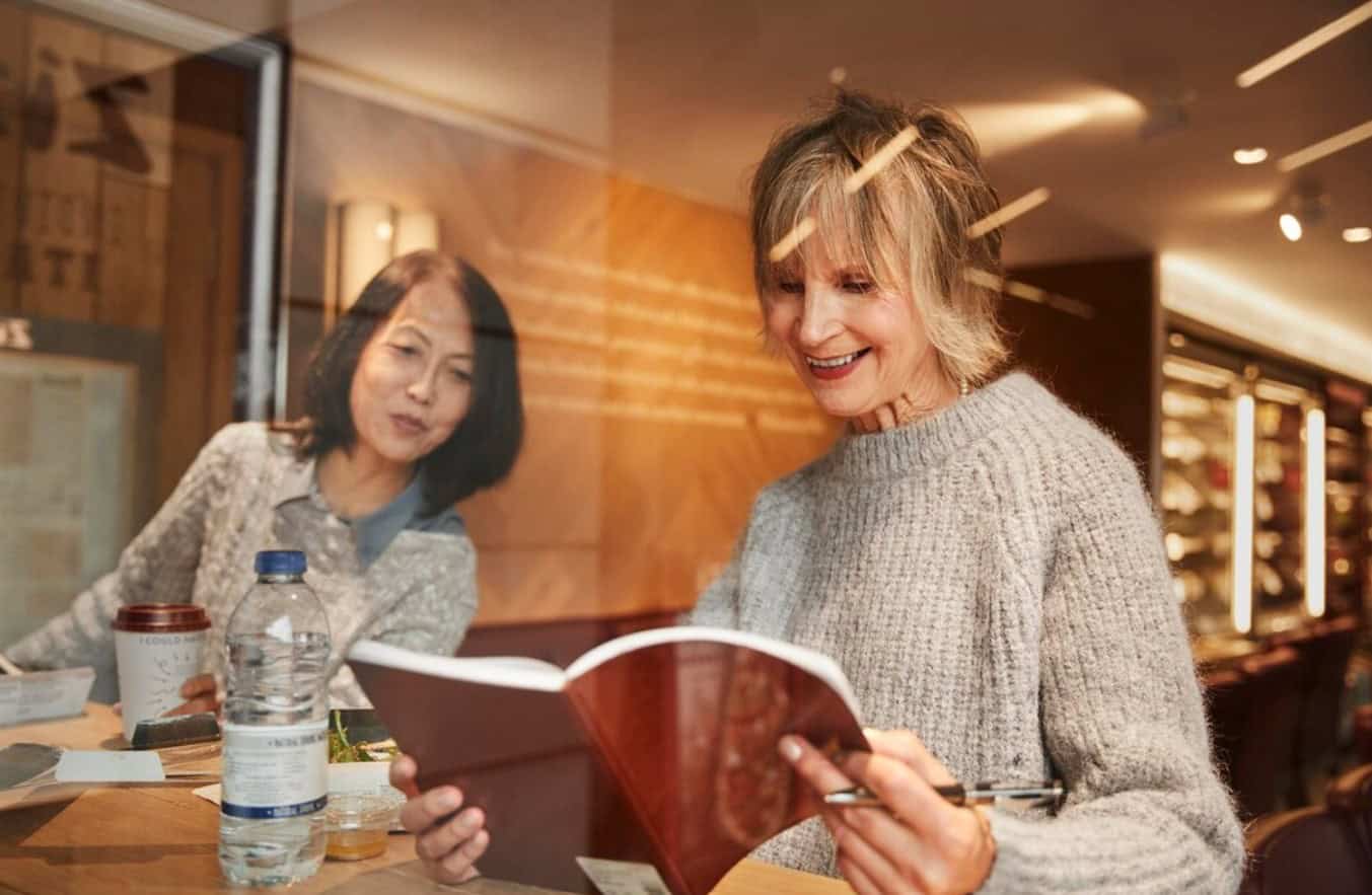 People reading on tablets in a cozy café, discussing online stories — symbolizing the rise of digital reading culture.